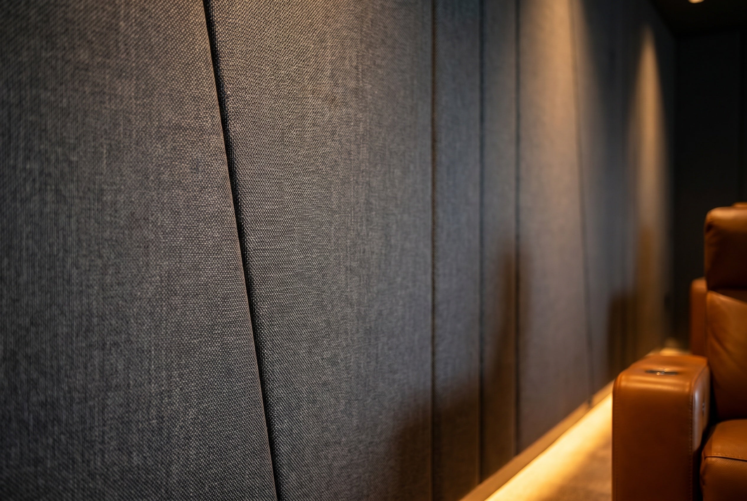 Textured gray wall with a brown leather chair in a dimly lit room