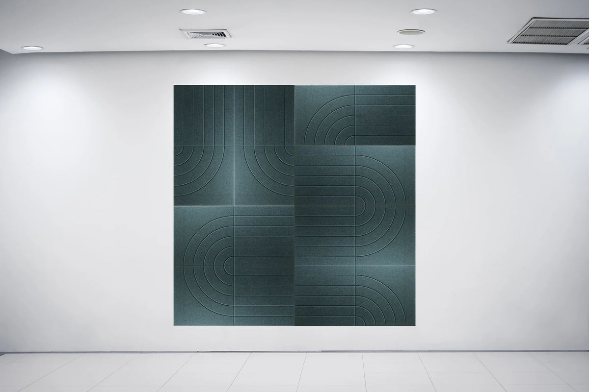 A large square abstract wall art piece with a dark teal-green geometric pattern, displayed on a white gallery wall in a minimalist room with a white floor and ceiling lights.