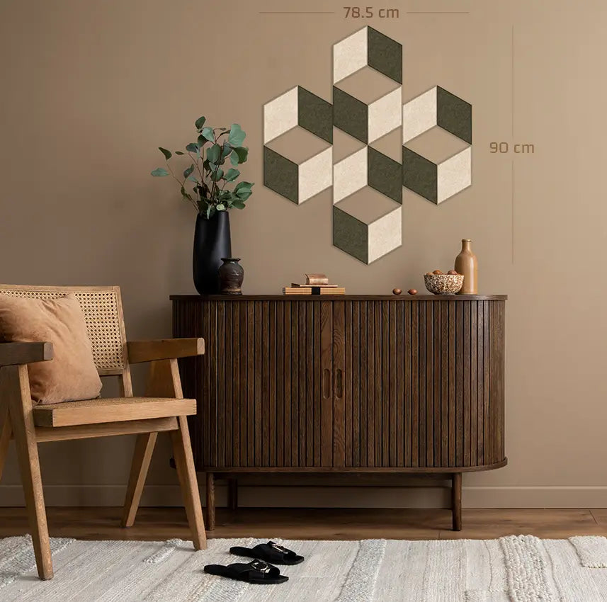 A styled interior scene showing a dark wood sideboard against a beige wall, with a geometric cube-pattern wall decor piece above it. A wooden chair with a cushion is partly visible on the left, and the room includes a rug, vase with greenery, and small decor objects.