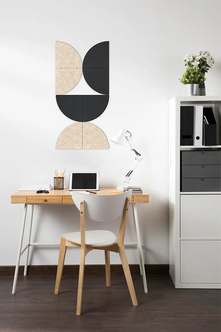 A wall panel with geometric shapes in black and beige colors mounted on a wall above a desk with office chairs and decorative items in a room.
