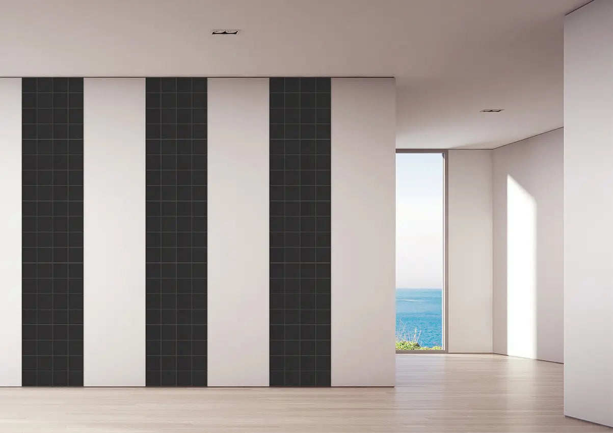 Modern interior room with alternating vertical black and white tiled wall panels, light wood flooring, and a large window opening to the ocean.