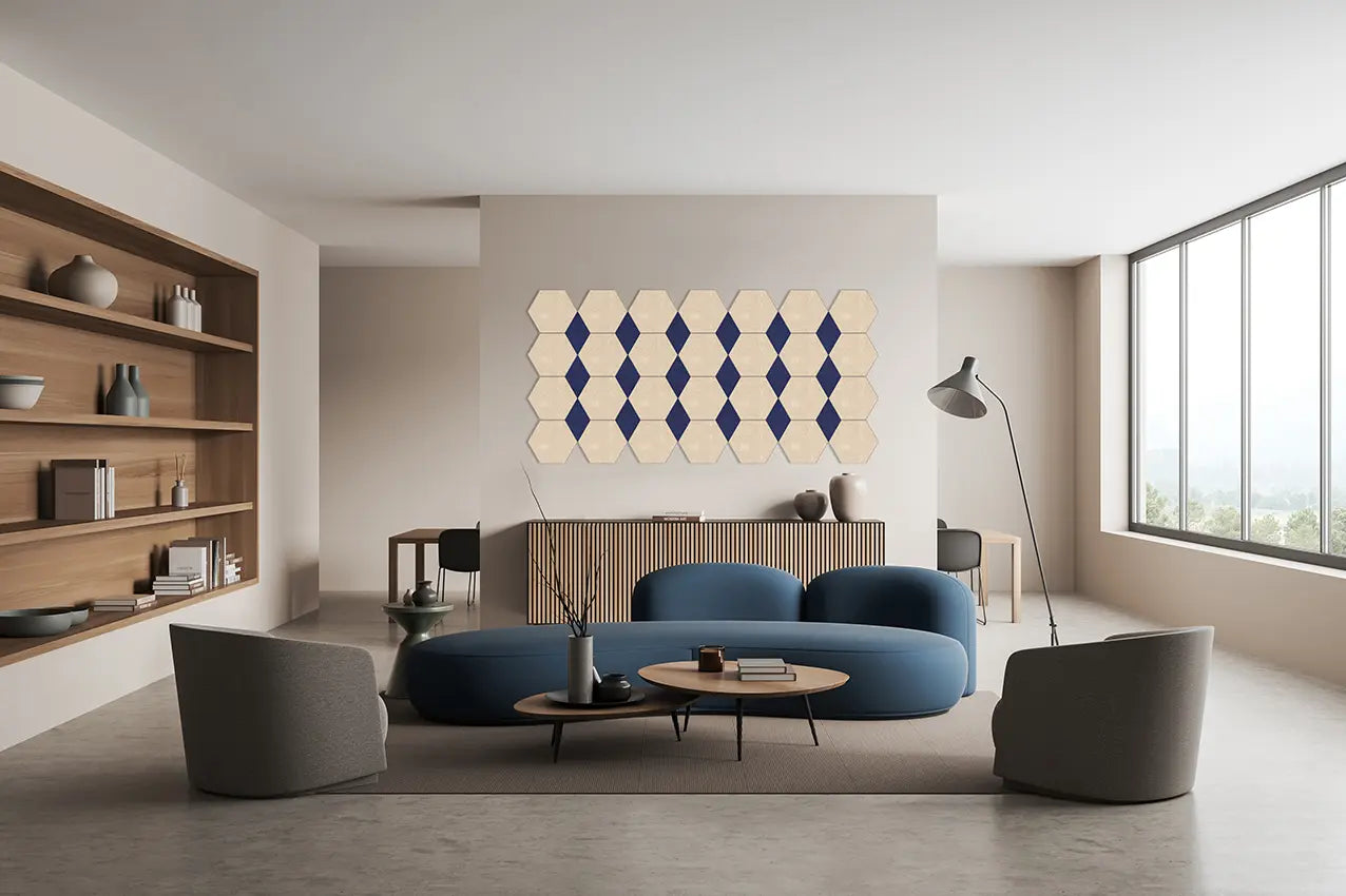 A modern living room featuring a blue curved sofa, gray armchairs, a round wooden coffee table, and a geometric hexagon wall art piece in cream and navy blue hanging on the wall above the sofa.