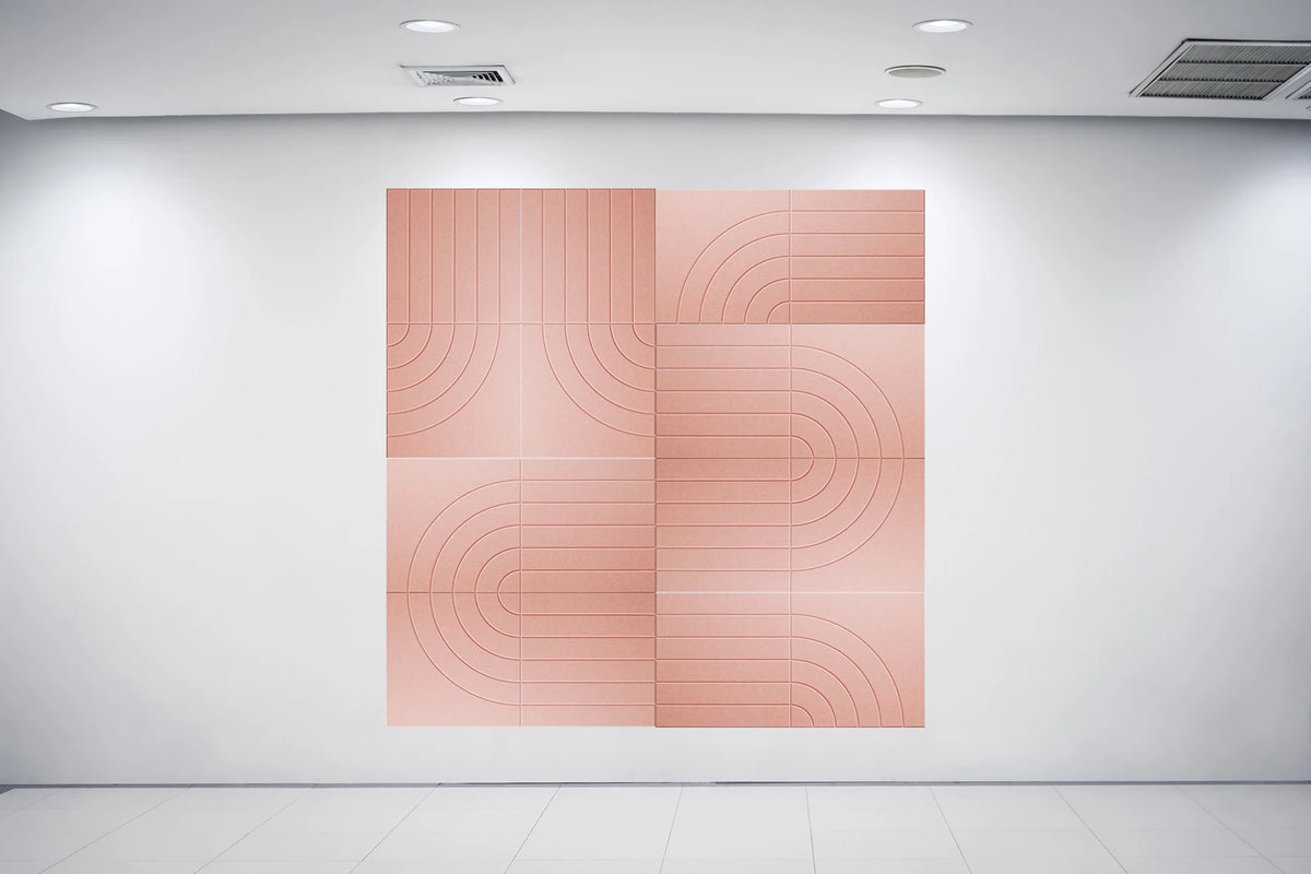 A large square abstract wall art piece in a warm peach-pink tone with curved linear patterns, displayed on a white gallery wall in a minimalist room with recessed lighting.