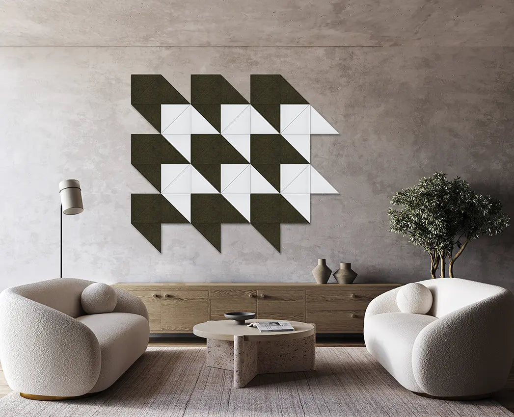 Abstract geometric artwork hanging on a wall in a living room setting with two white armchairs, a low table, and a bookshelf.