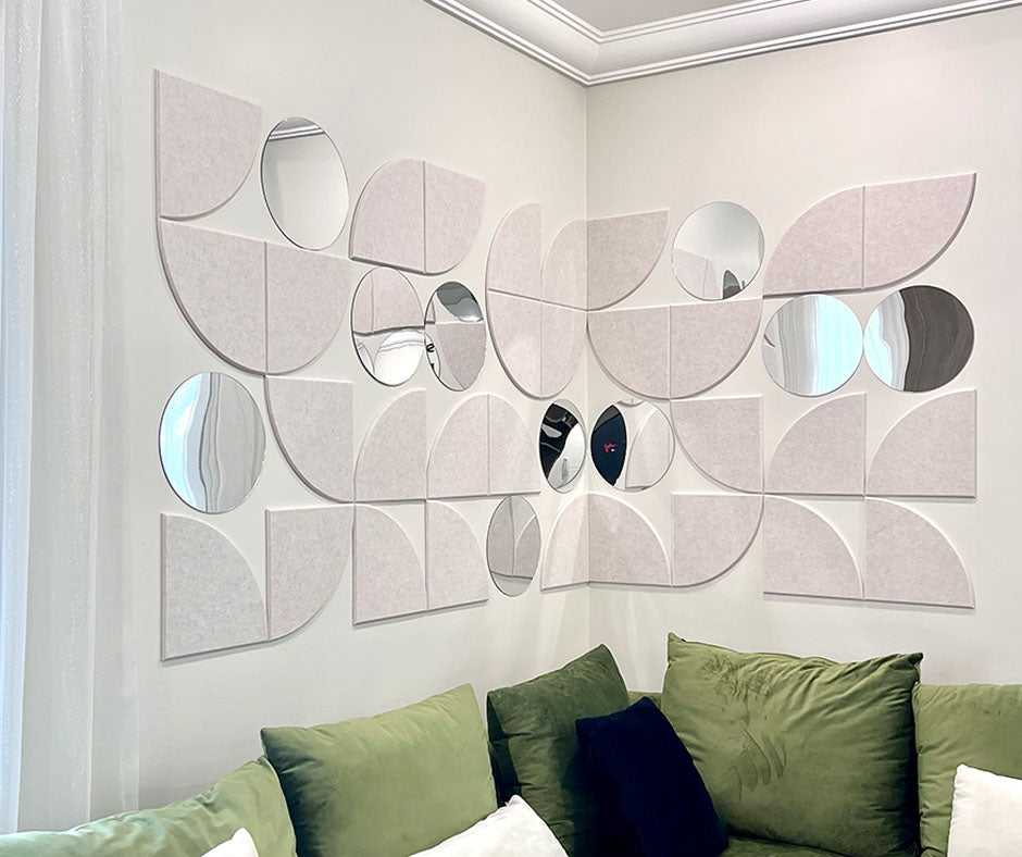 Decorative wall art with geometric mirrors on a white wall above a green sofa.
