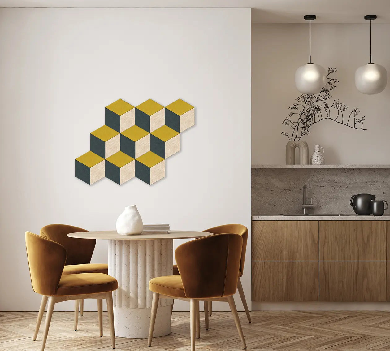 A modern dining room scene with a geometric wall art piece made of overlapping cube shapes in gold, cream, and dark green on a white wall above a round table and chairs. A kitchen area is visible in the background.