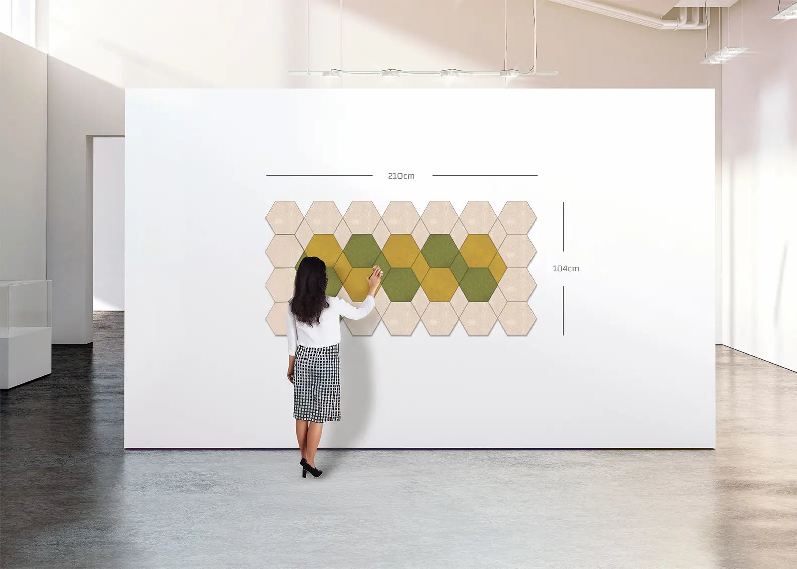 A woman stands in front of a large white wall displaying a hexagonal tile pattern with dimension markings (250cm by 304cm) in a modern, minimalist room with gray floors.
