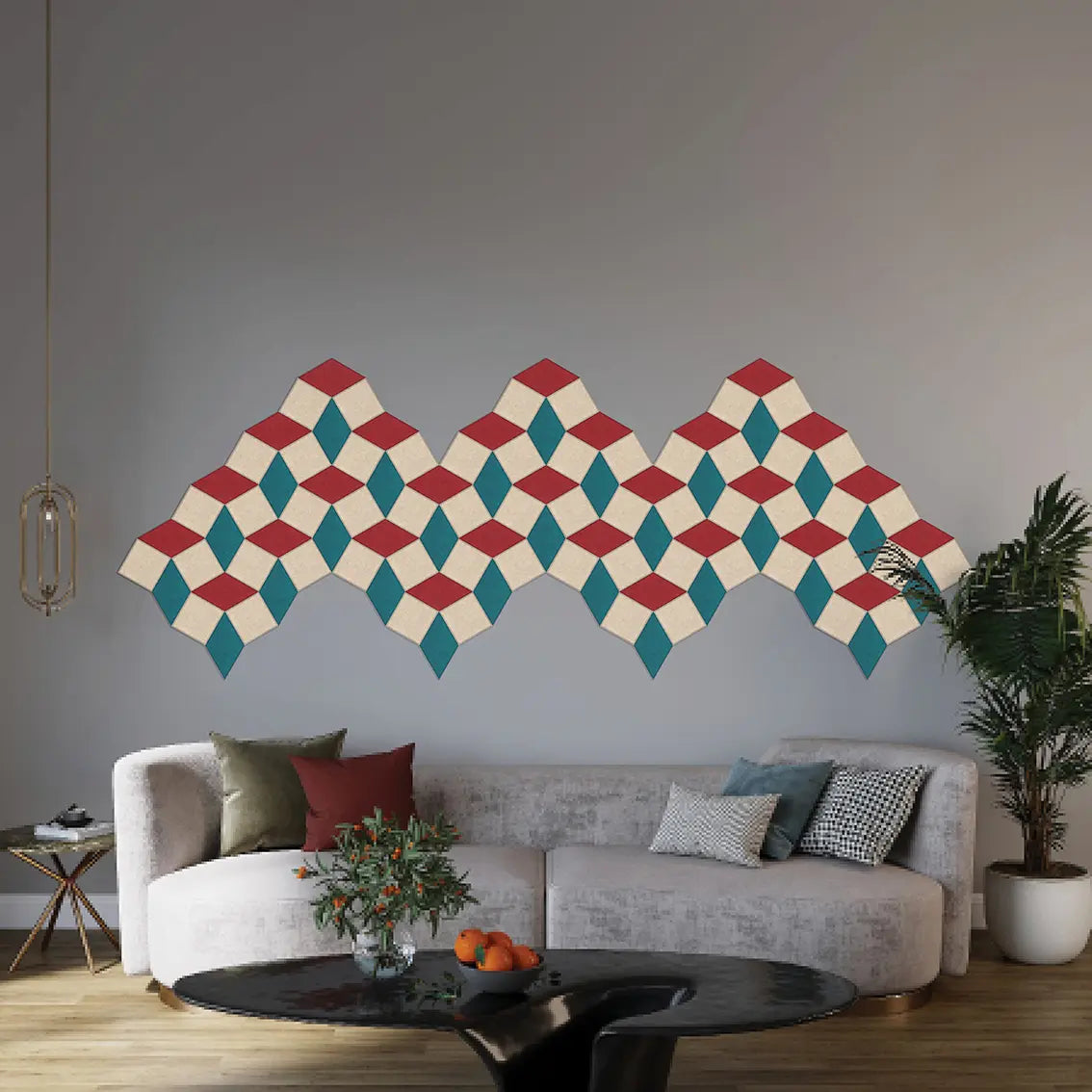 A geometric wall decal with a repeating 3D-effect diamond pattern in red, teal, and cream is displayed on a gray wall above a modern light gray sofa in a styled living room.