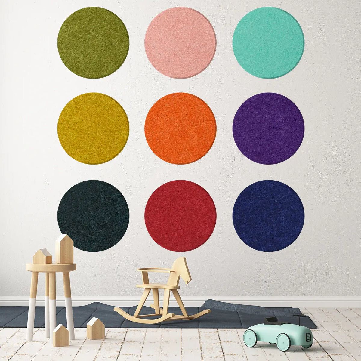 A wall adorned with multicolored circular polka dot panels in various sizes, with a wooden rocking horse and toy car on the floor in front of it.