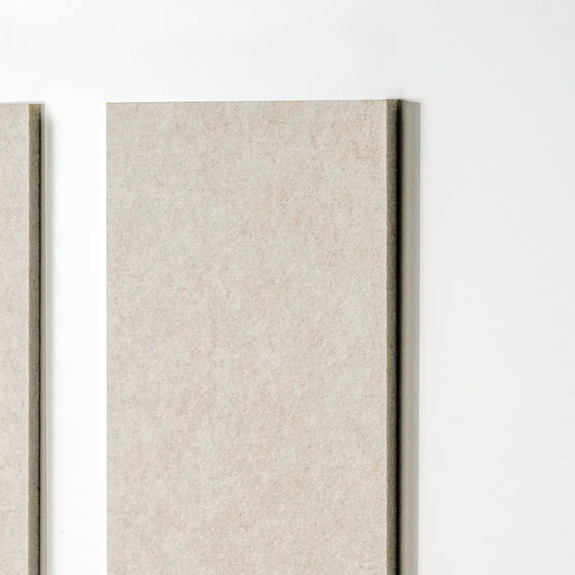A close-up of a rectangular tan textured panel or tile mounted against a white wall, with part of a second matching panel visible at the left edge.