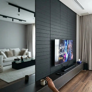 Modern living room with a television displaying a show, surrounded by stylish decor.