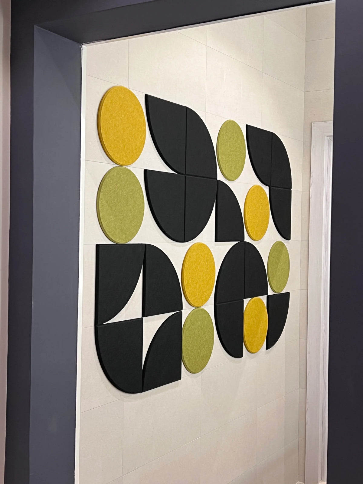 A wall-mounted artwork featuring a geometric pattern with black, yellow, and green shapes.
