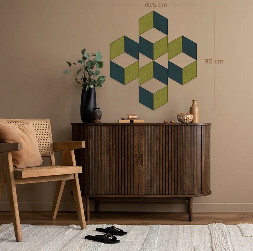 A styled interior scene showing a geometric wall art piece mounted above a wooden sideboard. The artwork consists of overlapping cube shapes in olive green, dark teal, and cream, with dimension labels reading 78.
