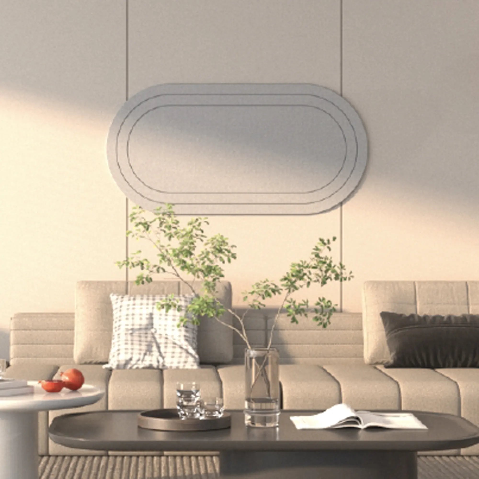 A modern living room scene featuring a beige sectional sofa with decorative pillows, a low dark coffee table with a glass vase and open book, and a large minimalist oval wall mirror hanging on the wall.