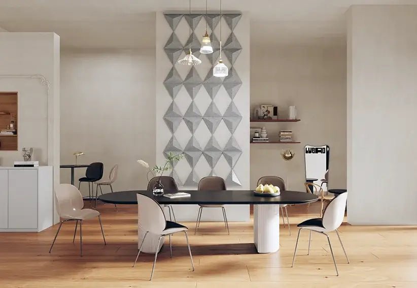 A modern room with a wall art featuring ten 3D triangles in varying shades of gray, dividing the space into two areas. There is a round dining table with chairs in the foreground and a kitchen in the background.